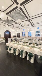 Eleganter, weiß dekorierter Festsaal mit gedecktem Hochzeitstisch.
