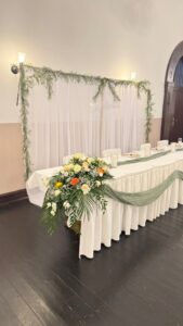 Ein elegant geschmückter Hochzeitstisch mit weißen und grünen Blumen.