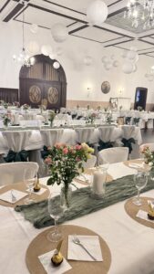 Festlich dekorierter Speisesaal mit langen, weiß eingedeckten Tischen.